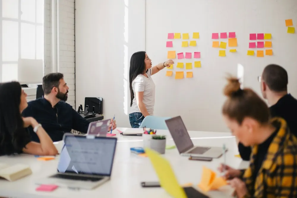 Professionals discussing ideas around a table during a workshop, with sticky notes on the wall